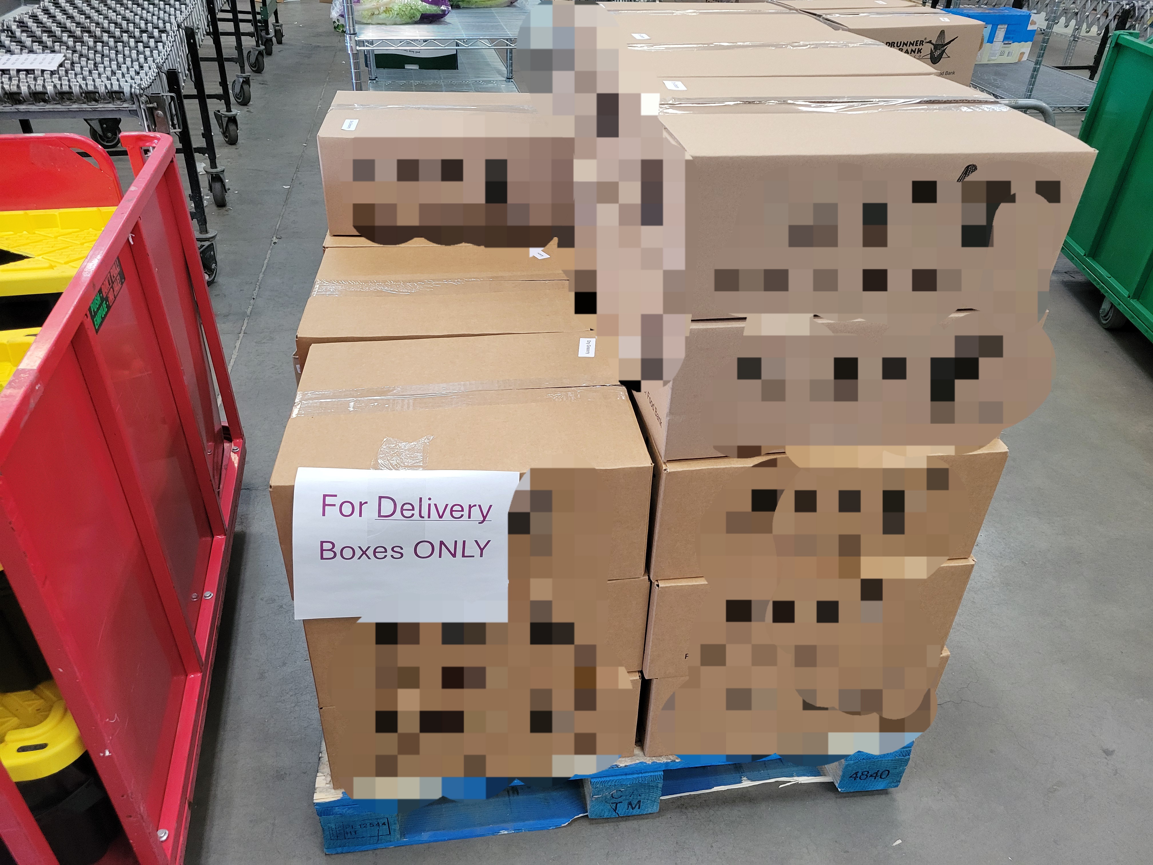 Cardboard boxes on pallet and sign that says for delivery boxes only on one.